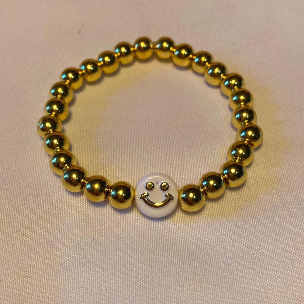 Gold beaded bracelet with a white and gold smiley face